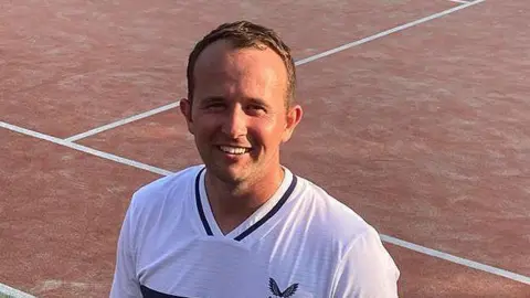 Tennis coach David Bryceland standing on a tennis court smilingcourt