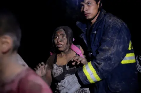 Reuters A rescue worker and a woman covered with ash