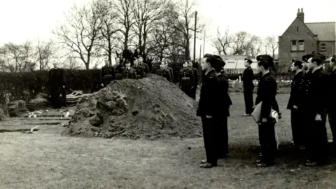 Yorkshire Air Museum A black and white photograph of military men in uniform holding a funeral in a field.