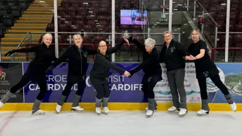 Girls on Tour The women in front of the Cardiff ice rink banner, wearing their uniforms.