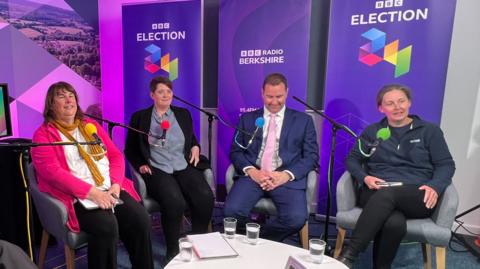 Two women and two men sat in front of purple, BBC election branding