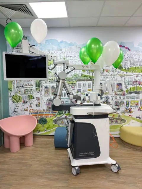 NHSGGC A machine on wheels with green and white balloons attached to it