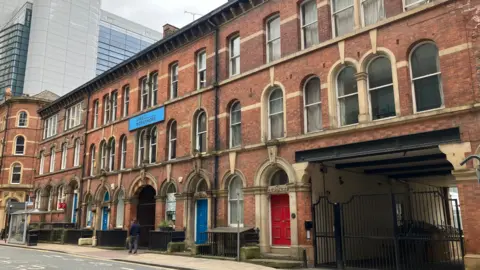 An exterior shot of Aire Street Workshop in Leeds - a red-brick terraced building with two stories of arched windows.