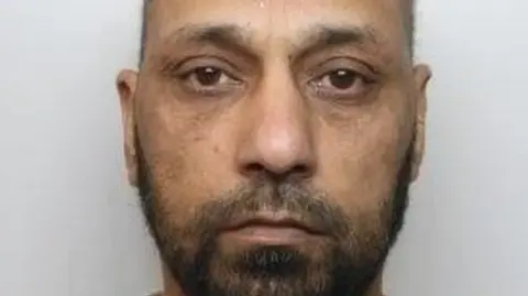 National Crime Agency A man with a black and grey beard staring straight ahead