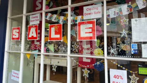 A close-up of the Dinghams shop window, showing items for sale. There are signs saying 'closing down sale' and '40% sale'.