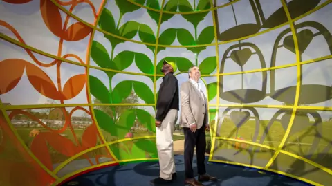 Maxim PR Yinka Ilori and Andrew Blevins look at the roof of the apple