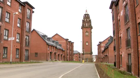 Red brick buildings on either side of a residential street with a red brick tower in the middle of the photo