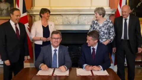 Reuters DUP MP Sir Jeffrey Donaldson and Tory Chief Whip Gavin Williamson signed the deal in front of their party leaders