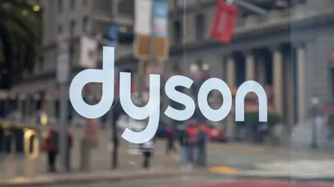 Dyson logo on glass storefront window with busy San Francisco downtown street reflected