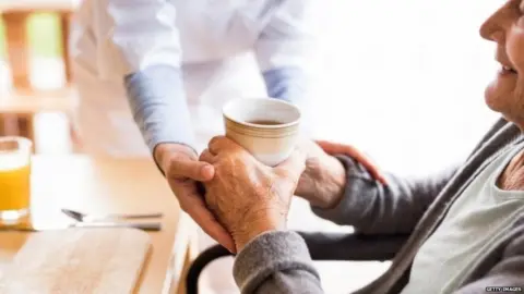 Getty Images A health visitor handing a woman a cup of tea