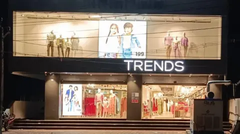 Reliance Retail A neon-lit facade of a Trends showroom lit up at dusk. 
