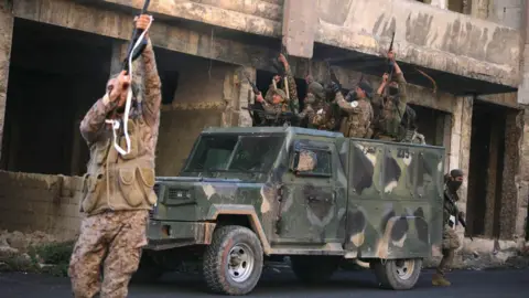 AFP Rebel fighters celebrate after they captured Maaret al-Numan in Syria's north-western Idlib province (30 November 2024)