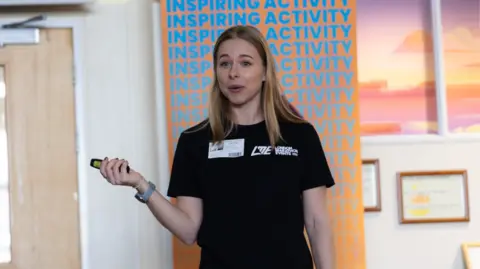 St Paul's Academy France White, wearing a London Marathon in schools t-shirt, speaks while holding a clicker remote in her hand