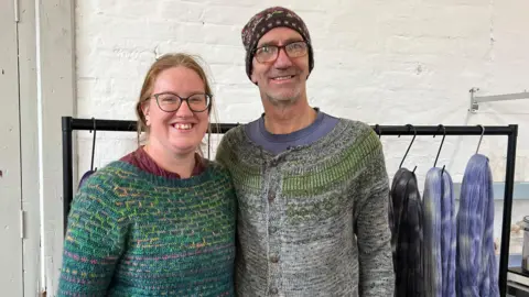 Becci and Markus Pamely-Bast are wearing clothes they have crocheted knitted using yarn they have dyed in their Weedon Bec workshop