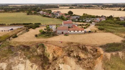 Qays Najm/BBC A photograph of an area of Trimingham in north Norfolk. The village is partly built on sandy cliffs on the coastline. The picture is an aerial and has been taken with a drone. It is not looking out to sea but captures how close housing is to the cliff top edge. 