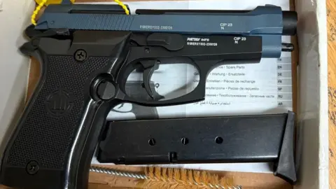 Derbyshire Police A black and blue automatic pistol, an ammunition magazine and a barrel cleaning brush in a box