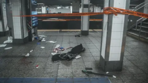 EPA Orange crime tape is used to cordon off the scene of blood and a machete on the train platform after a man was shot by New York Police Department.