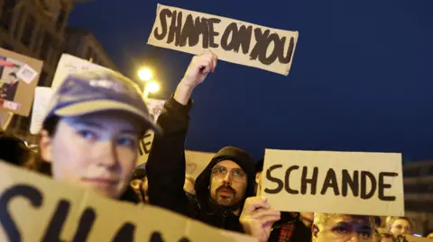 Reuters Activists protest against conservative German chancellor candidate Friedrich Merz's migration plans