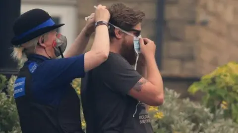 PA Community Police Officer helps man put on a dust mask