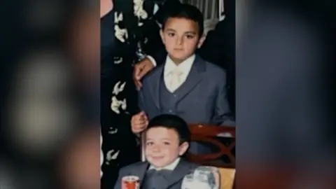 An old family photo showing a young Tommy Fury and his brother in grey suits