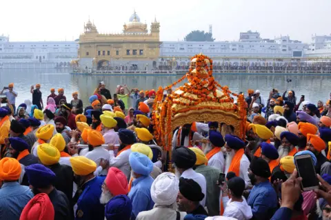 EPA Sikh devotees carrying the Sri Guru Granth Sahib ji - the holy book of Sikh religion - in a hand-held, golden carriage