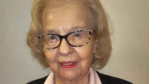 Baroness Golding Baroness Liln Golding who has short blonde hair and dark rimmed glasses, smiles at the camera.