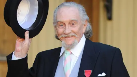 Fiona Hanson/PA Wire Roy Dotrice lifts his hat after receiving his OBE for services to drama in 2008