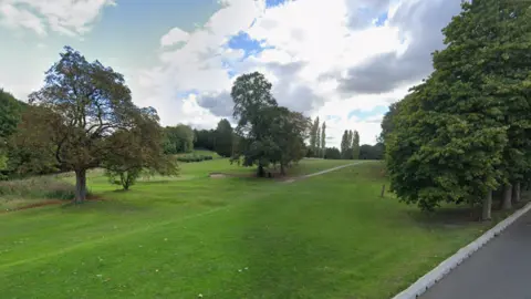 Google Street view shot from one side of the golf course. A sand bunker and large oak trees can be seen lining the golfing green.