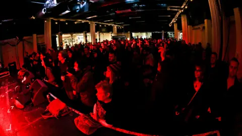 Hundreds of people stand in front of the stage at the Trinity Centre, 6 Music Festival