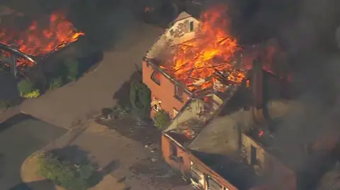 Aerial footage Flames and a plume of black smoke engulfing houses on residential street in Stourbridge  
