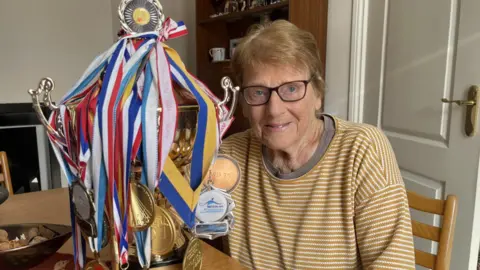 Edna Fletcher with a trophy and several medals 