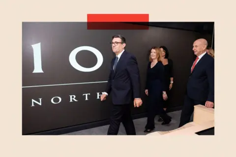 Reuters Britain's Prime Minister Andy Burnham walking past a sign which says 10 North 