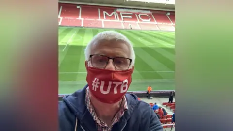 Nick Waites Nick Waites, pictured during the pandemic at the Riverside wearing a red face covering with hashtag UTB on it. It means Up the Boro.