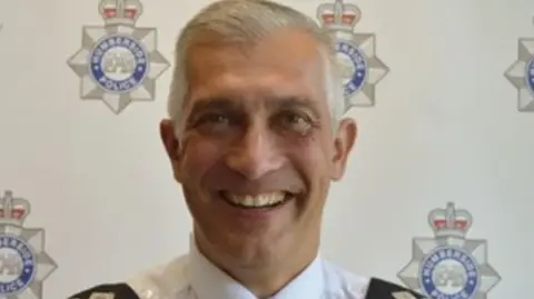 Paul Anderson, former chief constable of Humberside Police, smiles into the camera. He has grey hair and is wearing a white uniform