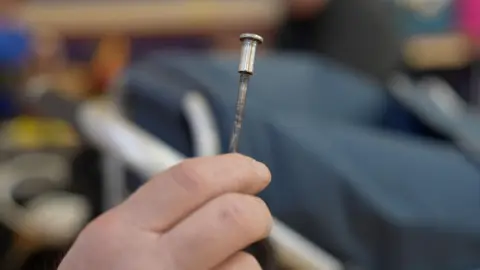 A metal rod with a broken fixing being held in front of Stephen's trolley.