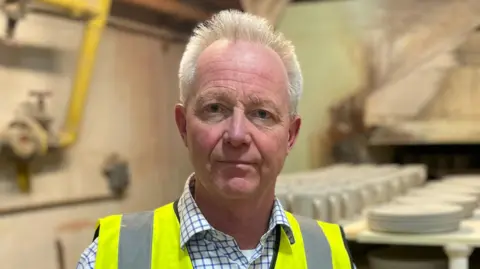 Man in checked shirt looks directly at the camera