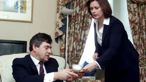 PA Media Gordon Brown: Chancellor of the Exchequer Gordon Brown is given a cup of coffee by his wife Sarah in his Downing Street apartment as he prepares to deliver his 2002 budget later