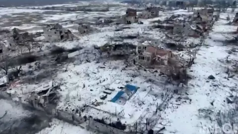 Donbass opeartivniy/Telegram View from the air, Marina's damaged house and empty blue swimming pool - there is snow on the ground and other damaged buildings nearby.