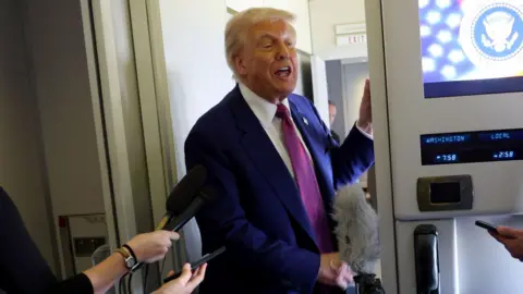 U.S. President Donald Trump talks to reporters aboard Air Force One.