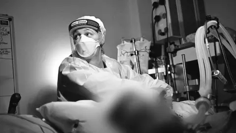 BBC Natasha Cumming tends to the ventaltion tubing of a Covid-19 patient