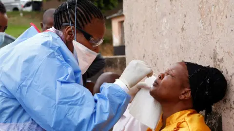 Reuters A health worker wearing a protective suit takes a swab from a resident during a door-to-door testing
