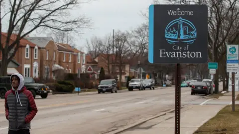 AFP/Getty Images A man walks by a sign welcoming people to the city of in Evanston, Illinois, on March 16, 2021