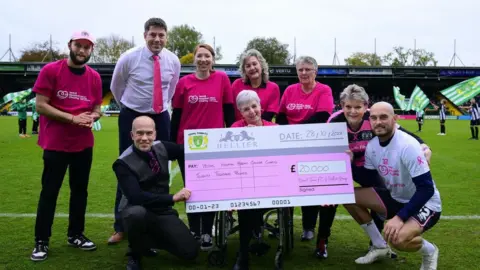 PPA Massive cheque on the pitch with people in pink kits