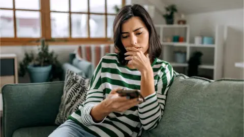 Getty Images Woman looks at phone - stock shot