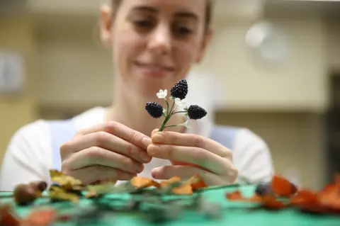 Getty Images Baker Sophie Cabot puts the finishing touches to cake decorations for the red velvet and chocolate wedding cake for Princess Eugenie of York and Mr Brooksbank in the kitchens at Buckingham Palace on October 10, 2018 in London, England