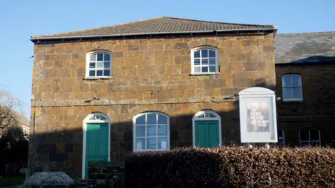 Bugbrooke Chapel, an old Georgian building with sash windows and two green doors. 