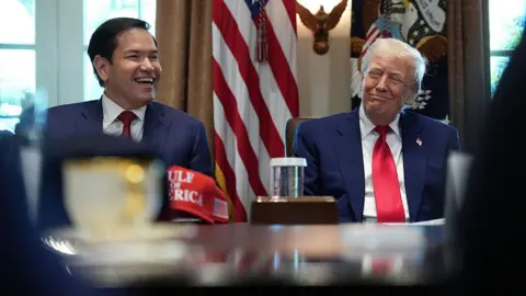 Getty Images President Donald Trump listens as U.S. Secretary of State Marco Rubio speaks during a Cabinet meeting at the White House