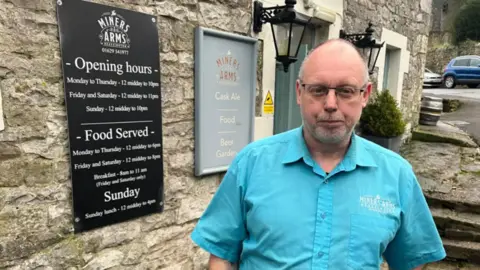 BBC A bald man wearing a blue shirt stood outside of a pub