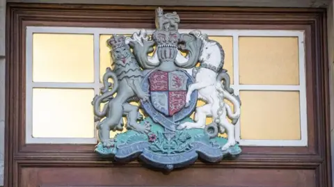 PA Media Crest above wooden door at the High Court in Belfast.