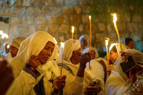 Sharon Eilo/SOPA Images/LightRocket/Getty Images An Ethiopian woman holds a candle while praying during the Holy Fire Ceremony of the Ethiopian Orthodox Church in Jerusalem